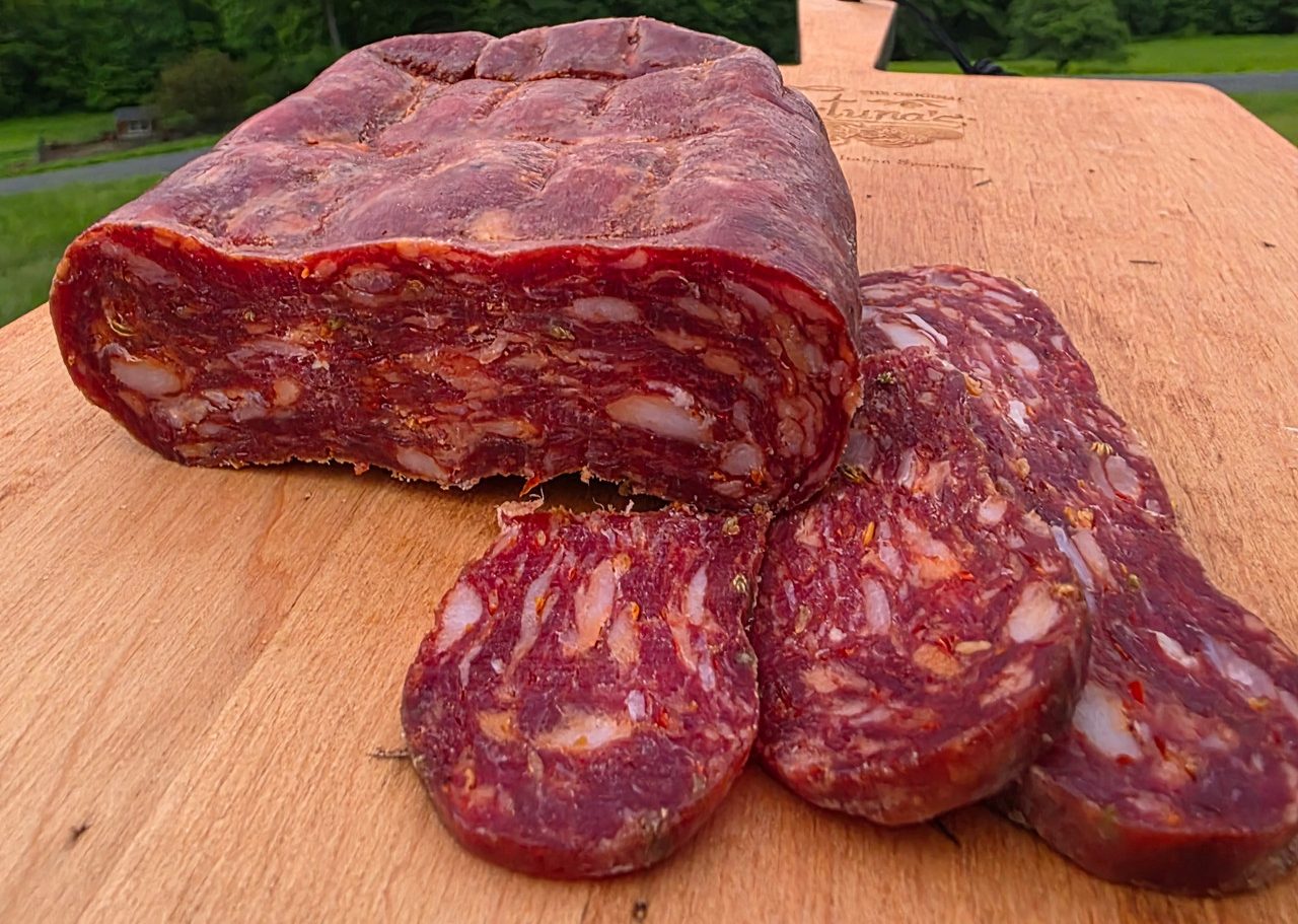 Sopressata in beef bung casing sliced on cutting board