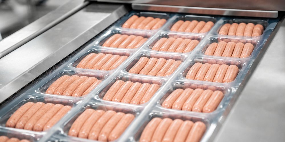 Thermoformed trays of sausages sealed on a rollstock packaging line