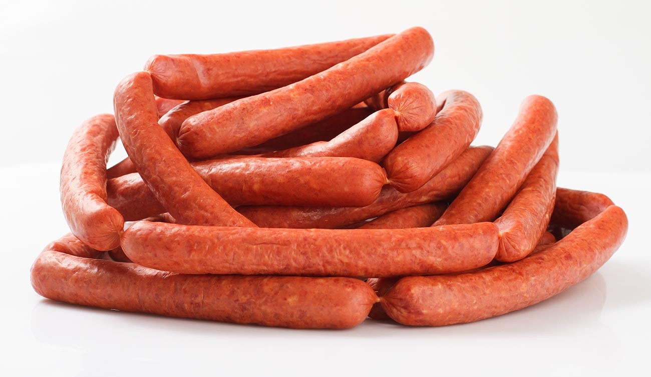 Frankfurters in natural sheep casings on wooden board